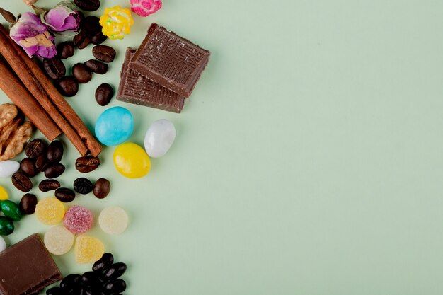 Top view of nuts in chocolate marmalade candies coffee beans and cinnamon sticks on the table with copy space