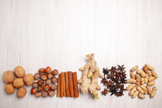 Top view nuts and cinnamon cinnamon sticks peanuts walnuts hazelnuts on the white table