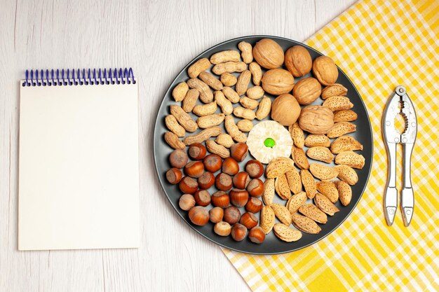 Top view nuts composition fresh walnuts peanuts and hazelnuts inside plate on white desk nut many tree plant snack shell