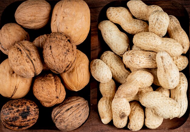 Top view of nuts peanuts in shell and whole walnuts on wooden background