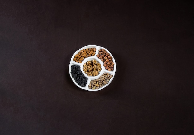 Top view nuts plate with dry fruits on a black table.