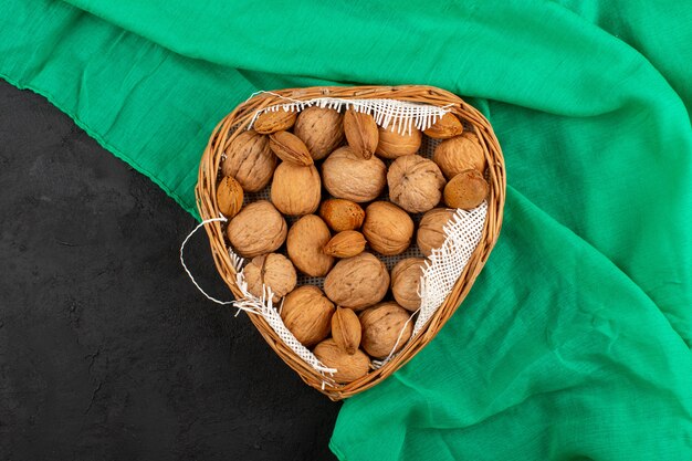 top view nuts walnuts inside brown basket on the green tissue and grey