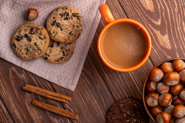 Vista superiore dei biscotti di farina d'avena con gocce di cioccolato e cacao e una tazza con bevanda al cacao su un legno