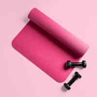 Бесплатное фото Вид сверху розового коврика для фитнеса и двух черных гантелей, изолированных на розовой поверхности
