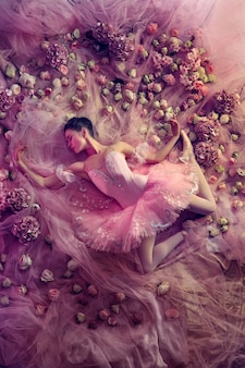 꽃으로 둘러싸인 핑크 발레 투투에서 아름 다운 젊은 여자의 상위 뷰
