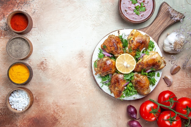 Бесплатное фото Вид сверху курицы с красочными специями, соусом из курицы с зеленью, луком, помидорами и цветоножками