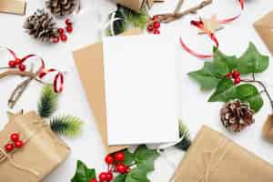 Бесплатное фото Вид сверху рождественской композиции с подарочной коробкой, лентой, еловыми ветками, шишками, анисом на белом столе