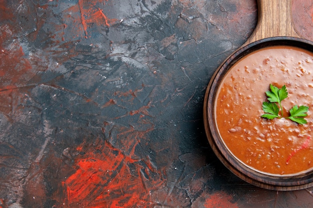 Бесплатное фото Вид сверху классического томатного супа на коричневой разделочной доске на смешанном цветном фоне