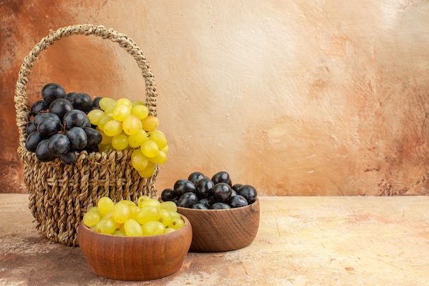 Вид сверху гроздей желтого и черного винограда в деревянной корзине и в небольших коричневых горшках