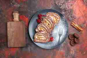 Бесплатное фото Вид сверху вкусных бисквитных рулетов с печеньем на темной поверхности