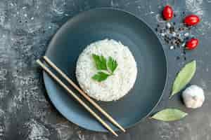 무료 사진 검은 접시에 녹색과 젓가락으로 제공되는 맛있는 쌀 식사의 상위 뷰 어두운 배경에 고추 마늘 토마토