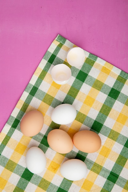 무료 사진 복사 공간 보라색 배경에 격자 무늬 천으로 달걀 껍질과 계란의 상위 뷰