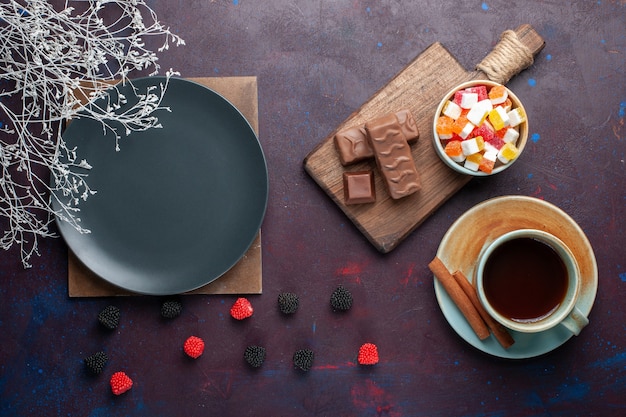 Бесплатное фото Вид сверху пустой темной круглой тарелки с чаем и конфетами на темной поверхности