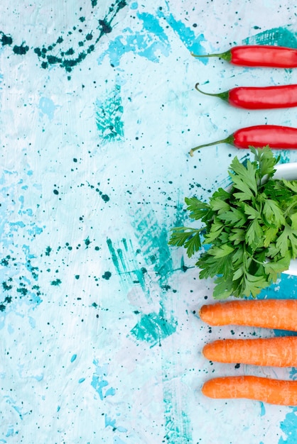 Бесплатное фото Вид сверху на свежую зелень, изолированную внутри тарелки, с пряным красным перцем и морковью на ярко-синем, зеленом листе