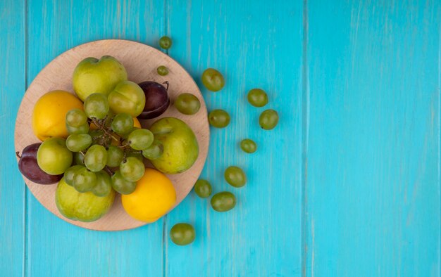 무료 사진 복사 공간이 파란색 배경에 절단 보드와 포도 열매에 포도 pluots 자두 nectacots로 과일의 상위 뷰