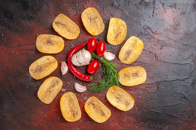 Бесплатное фото Вид сверху домашних вкусных хрустящих чипсов с красным перцем, чесноком и зелеными помидорами на темном столе