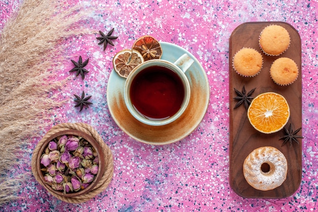 無料写真 淡いピンクの表面にオレンジスライスとお茶のカップと小さなケーキの上面図