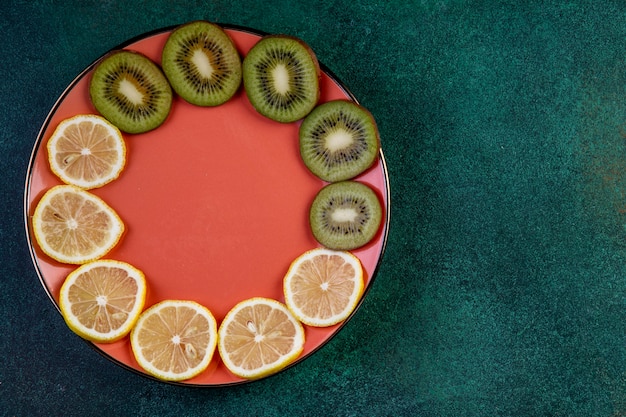무료 사진 복사 공간 어두운 녹색에 접시에 슬라이스 키 위와 레몬의 상위 뷰