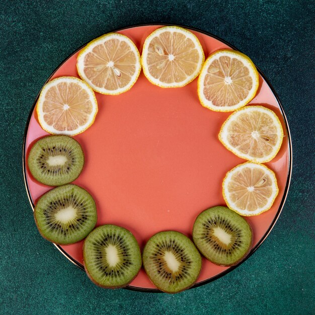 무료 사진 진한 녹색 접시에 얇게 썬된 키 위와 레몬의 상위 뷰