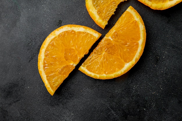 Бесплатное фото Вид сверху нарезанные апельсины на черной поверхности
