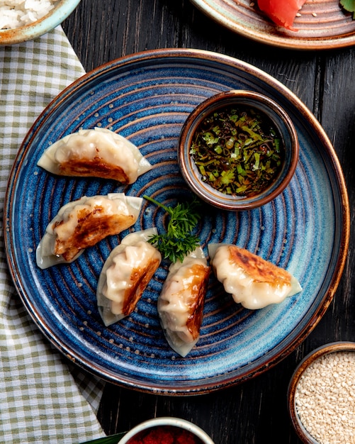 무료 사진 고기와 야채와 함께 전통적인 아시아 만두의 평면도 소박한 테이블에 접시에 간장 역임