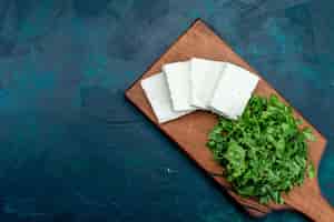 Бесплатное фото Вид сверху белого сыра со свежей зеленью на темно-синей поверхности