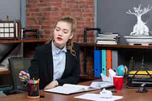 Бесплатное фото Вид сверху молодой леди, сидящей за столом и складывающей ручку в пенале в офисе