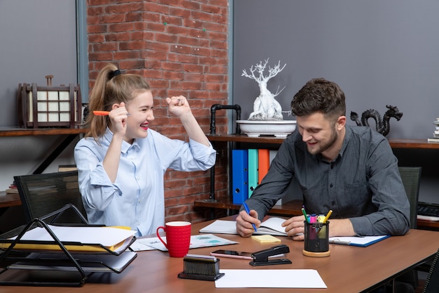 Бесплатное фото Вид сверху молодой целеустремленной и трудолюбивой улыбающейся офисной команды, сосредоточенной на одной проблеме в офисной среде