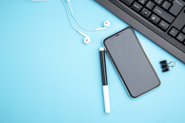 Top view of office concept with mobile phone headphone on blue surface