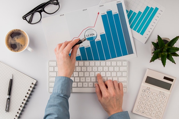 Top view of office desk with growth chart analyzed with magnifying glass