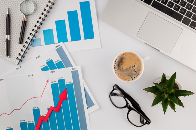 Top view of office desk with growth chart and coffee with glasses