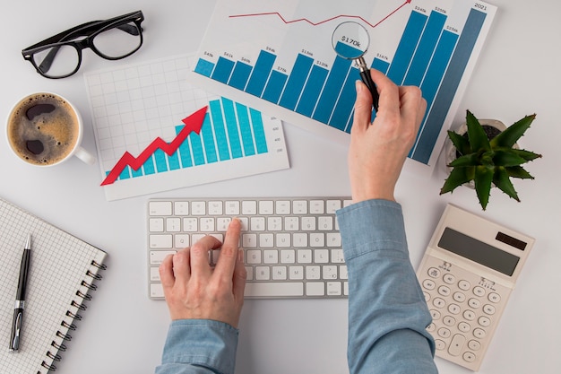top view of office desk with growth chart and hands with keyboard
