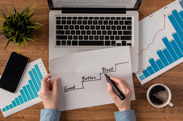 Top view of office desk with growth chart held by hands