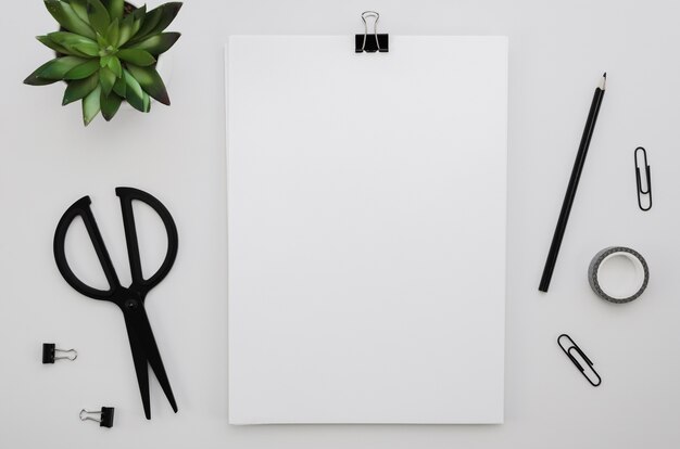 Top view of office supplies with scissors and plant