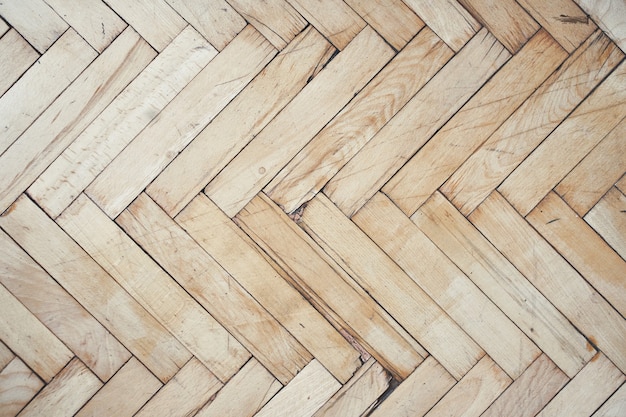 Top view of old brushed and distressed wooden parquet floor made from many racks in herringbone pattern