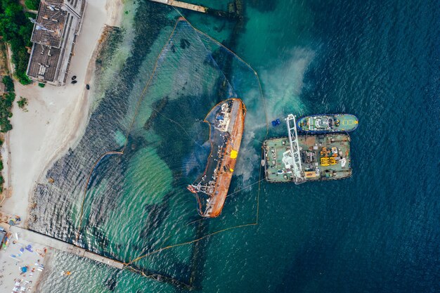 Top view of an old tanker that ran aground and overturned on the shore near the coast
