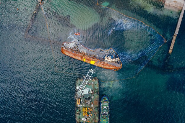 Top view of an old tanker that ran aground and overturned on the shore near the coast.