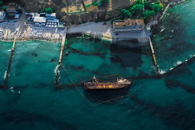 海岸近くの海岸で座礁して転覆した古いタンカーの上面図。