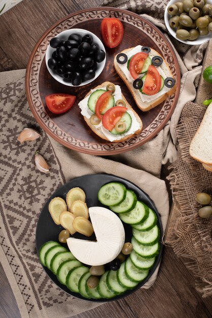 Вид сверху оливковых бутербродов с хлебом и нарезанными огурцами