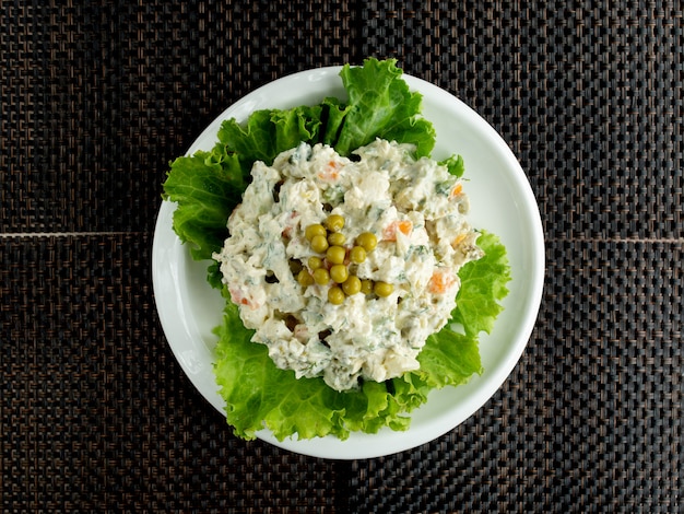 Free photo top view of olivier salad bowl garnished with lettuce