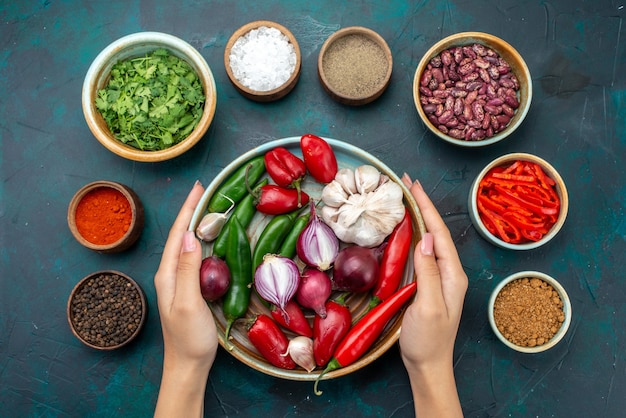Вид сверху лук и чеснок с зеленью и приправами на темно-синем столе овощные пищевые ингредиенты салата