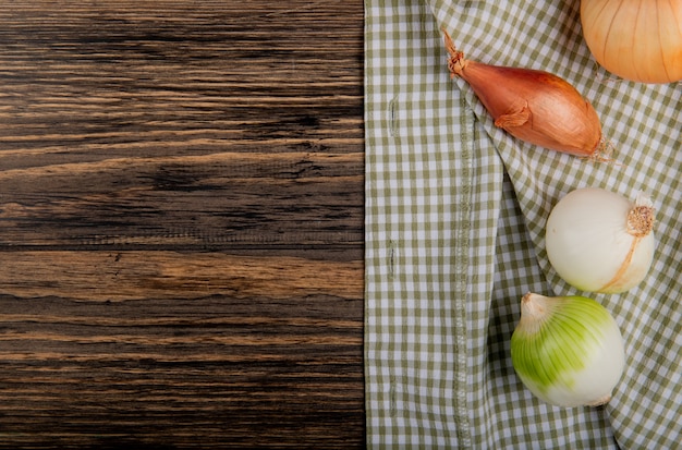 Top view of onions as shallot sweet and white ones on plaid cloth and wooden background with copy space