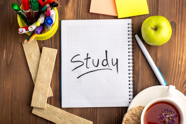 Free photo top view open blue copybook with crackers cup of tea and green apple on brown desk