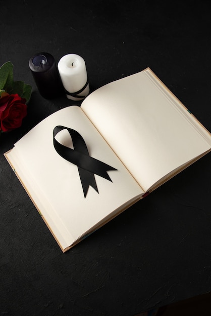 Free photo top view of open book with black mourning bow on a dark wall