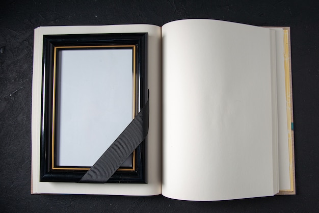 Top view of open book with picture frame on dark wall