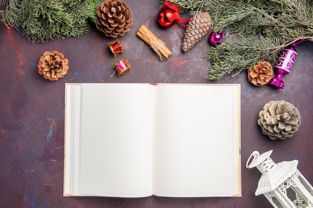 Top view of open copybook with christmas tree and cones on black