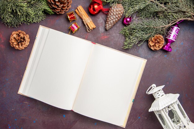 Top view of open copybook with christmas tree and cones on black