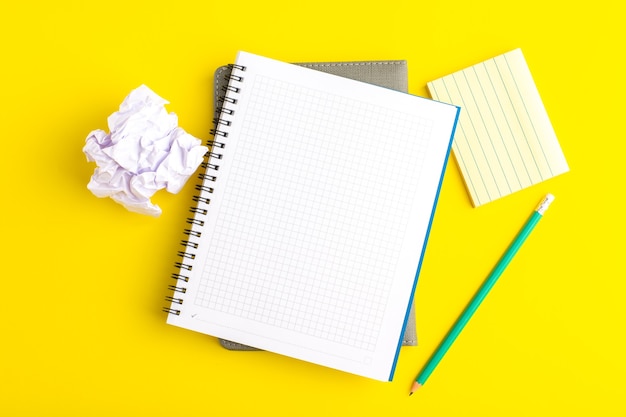 Top view open copybook with pencil on yellow surface