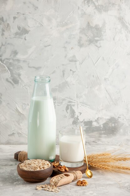 Top view of open glass bottle cup filled with milk spoon and walnut oats in brown pot on ice background