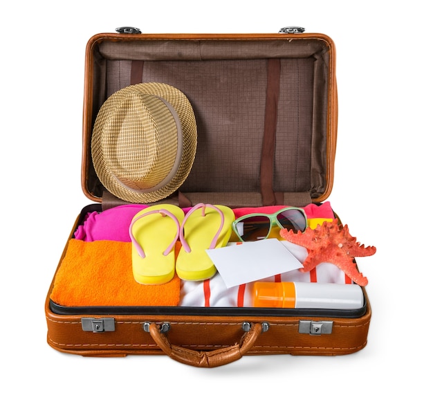 Top view of an open suitcase with full of summer stuff on blue background
